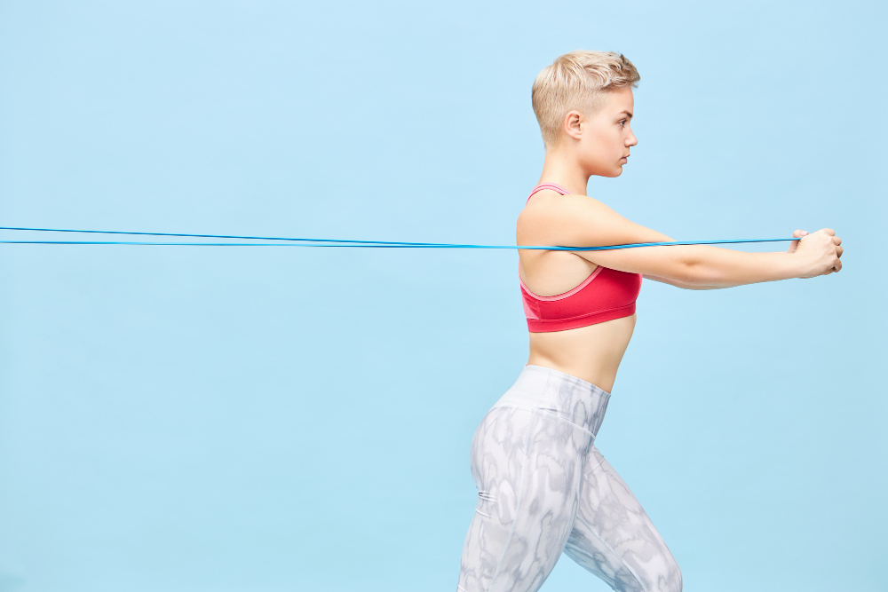 side-view-fashionable-young-caucasian-female-with-sporty-fit-body-pixie-hairstyle-pulling-strap-with-hands-front-her-pretty-girl-trendy-sportswear-training-using-resistance-band