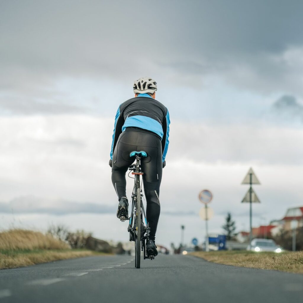 cyclist-riding-his-bike-on-empty-road-royalty-free-image-1676591828