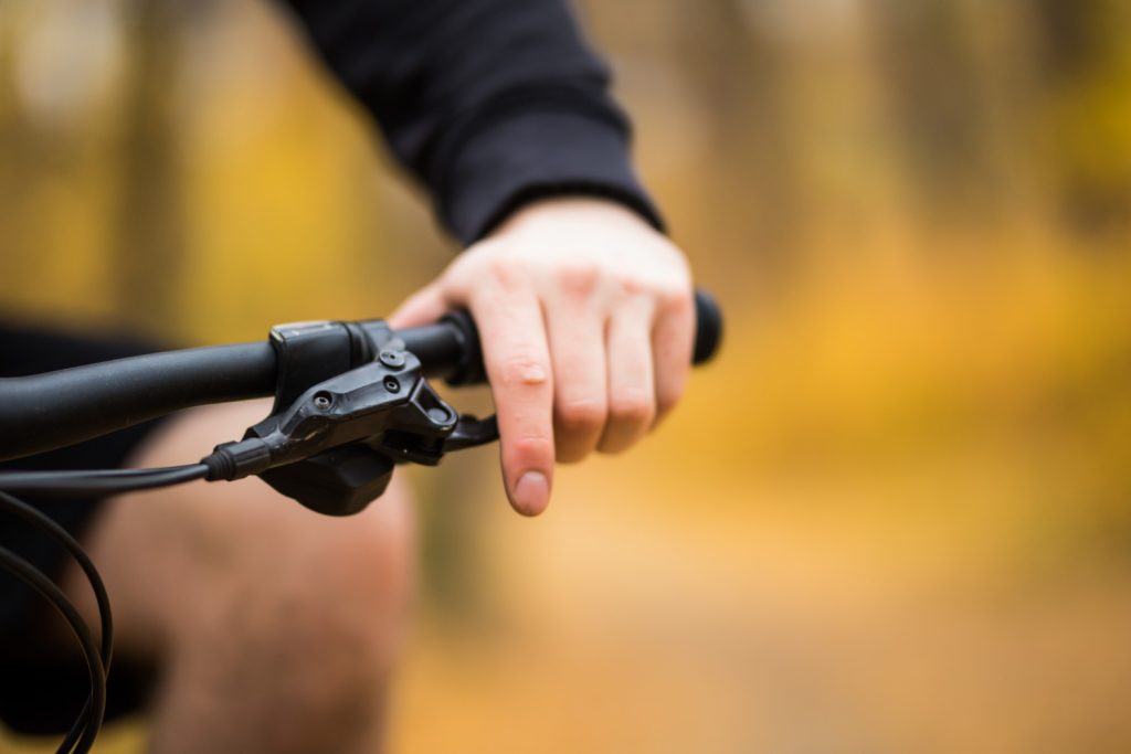 man-riding-his-bicycle-through-park-pathway-alongside-colorful-rail-close-up-view-back-his-hand-handlebar