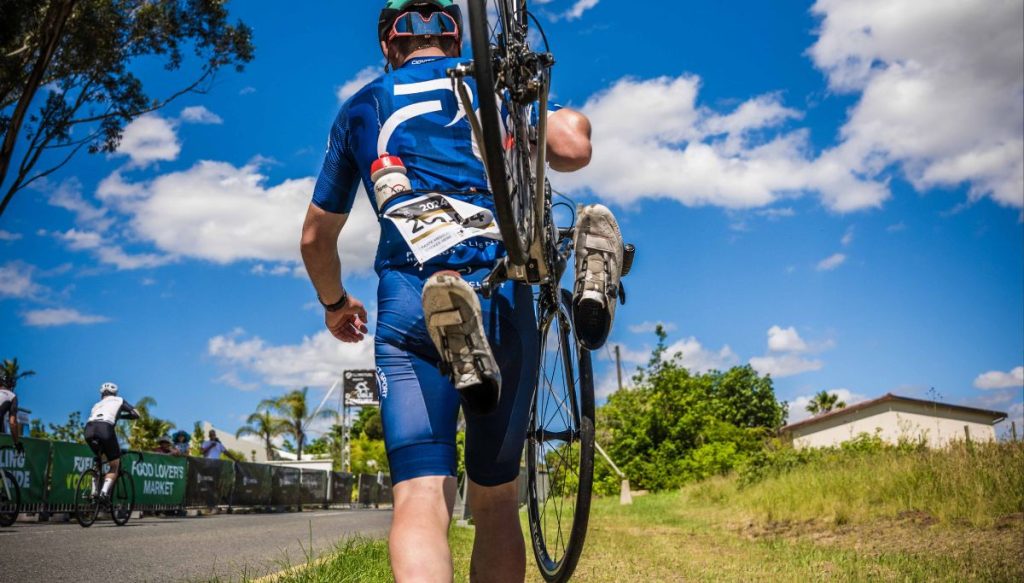 A cyclist walking carrying his bike